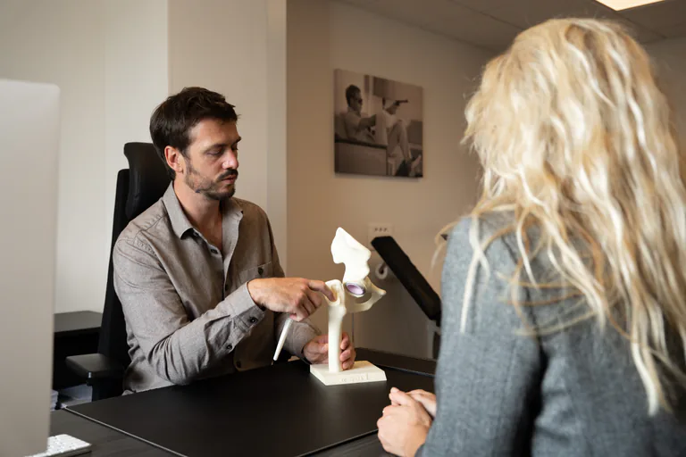Consultation — le Dr Devaux présente un modèle anatomique de hanche